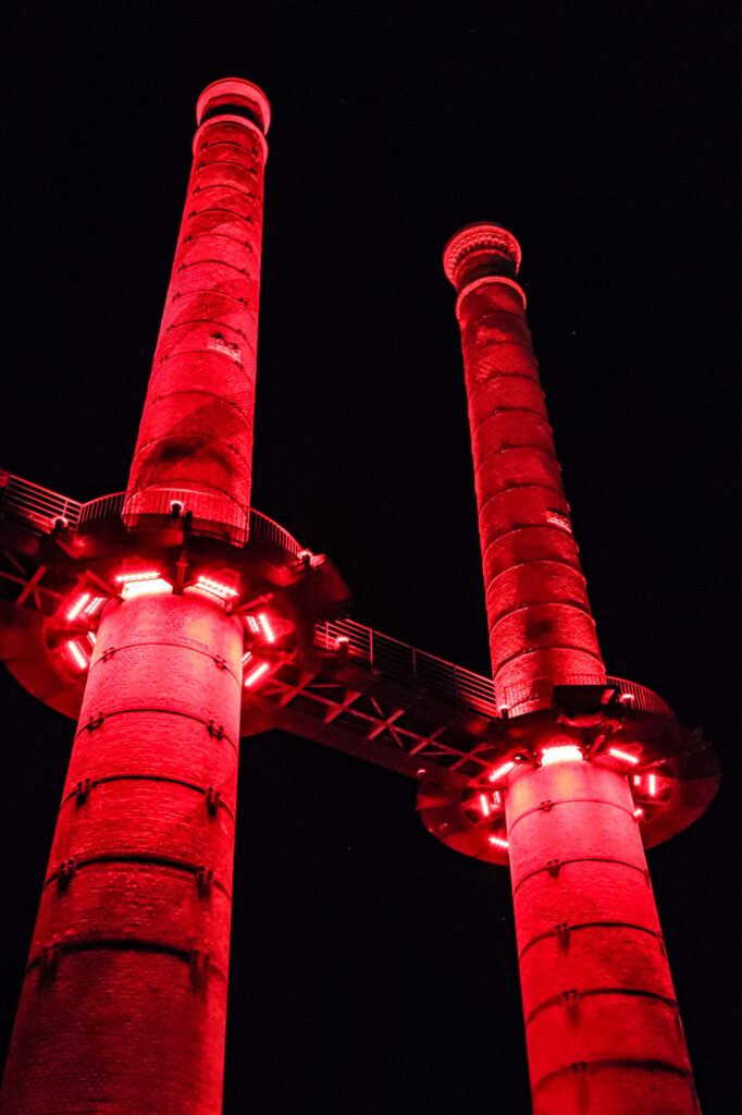  - Anciennes cheminées de la centrale thermique de la manufacture d'armes de Châtellerault,     dans laquelle des milliers d’ouvriers ont fabriqué de nombreuses armes lors de la secondes guerre mondiale, notamment sous l’occupation allemande. La nuit, un éclairage rouge illumine les deux tours, rappelant la couleur du sang versée lors d’une guerre meurtrière.