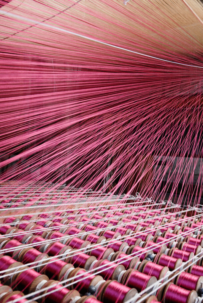  - Atelier de tissage dans l'ancienne manufacture Le Manach. Sous le métier à velours, se trouve la cantre au plan incliné, sur laquelle sont disposées les bobines de la chaine poil pour le tissage d'une étoffe de velours de Genes. La Maison Le Manach a été rachetée par Pierre Frey en 2014.