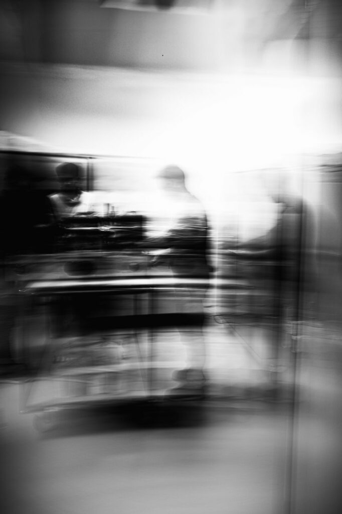 Be Monochrom - Chez PASQAL, l’ordinateur quantique ne se présente pas comme une machine spectaculaire, mais comme un espace de précision, de réglage et d’attention. Autour du dispositif, les ingénieurs composent une chorégraphie silencieuse faite de gestes mesurés, d’observations et d’ajustements. Le noir et blanc révèle cette tension entre la densité industrielle de la machine et l’invisible qu’elle manipule : atomes, lumière, vide, calcul. Cette série cherche à montrer une industrie nouvelle, où la matière semble s’effacer au profit d’une précision presque immatérielle, sans que la main humaine disparaisse.  Photo 1 : États superposés: Chez PASQAL, des ingénieurs interviennent autour d’un ordinateur quantique en cours de fabrication et de réglage. Le flou de mouvement superpose les silhouettes et fait écho, dans l’image, au principe de superposition propre au calcul quantique.
